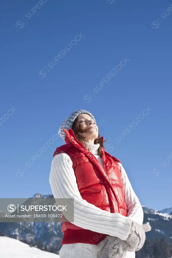 Woman standing with eyes closed in winter landscape, Tannheimer Tal, Tyrol, Austria