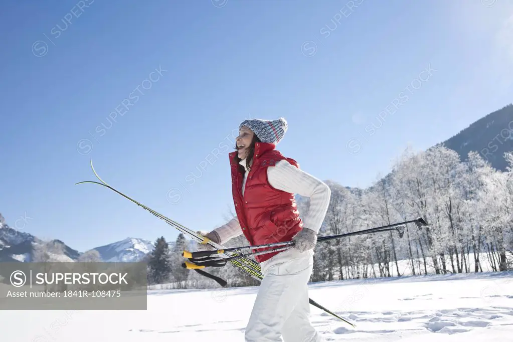 Laughing woman with skis in winter landscape, Tannheimer Tal, Tyrol, Austria