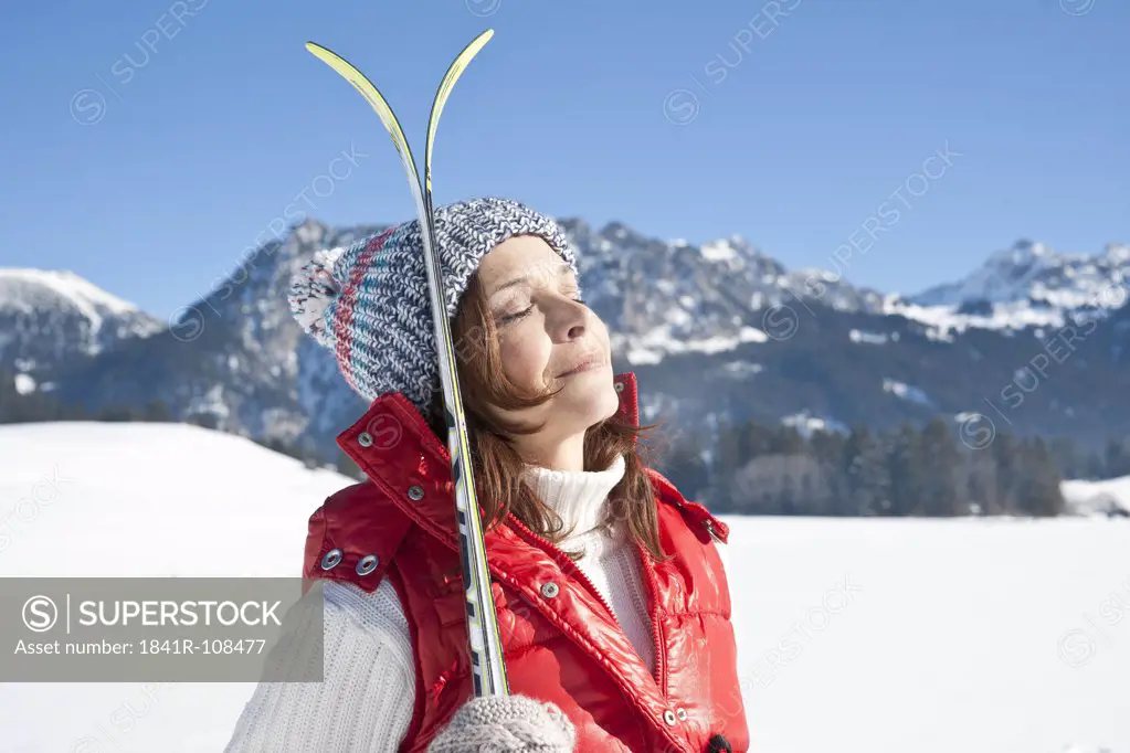 Woman with skis in winter landscape, Tannheimer Tal, Tyrol, Austria