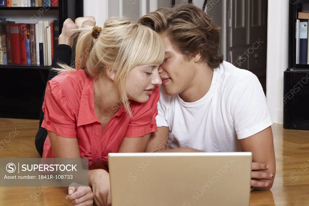 Young couple using laptop on the floor
