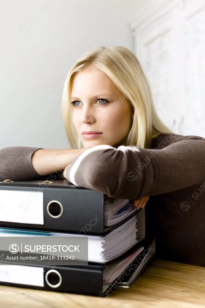 Serious blond woman leaning on file folders