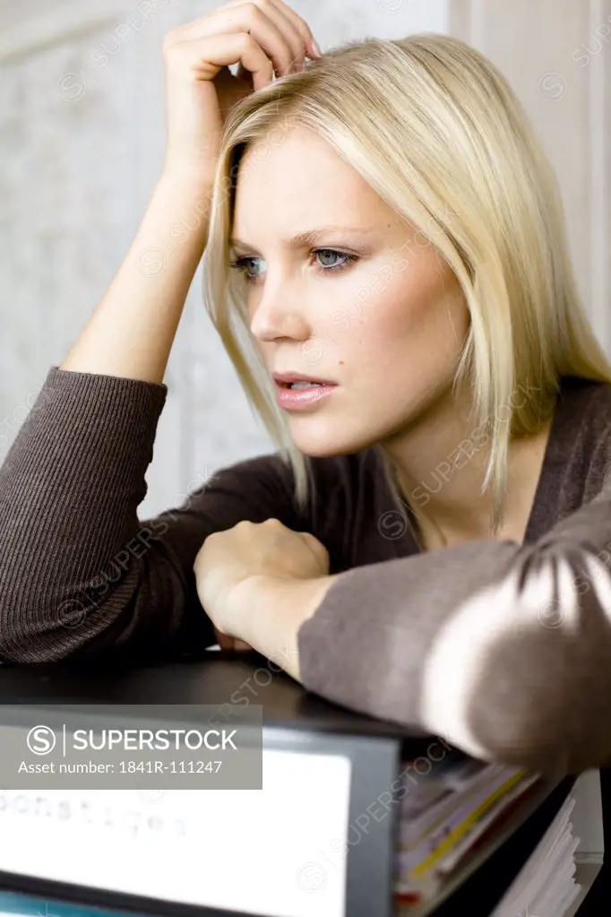 Serious blond woman leaning on file folders