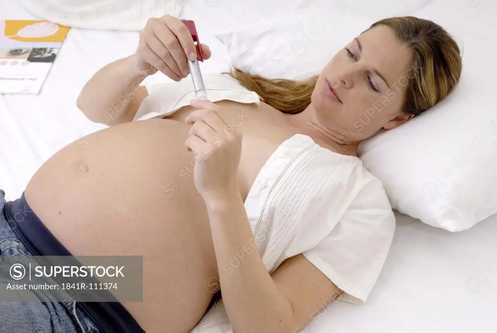Pregnant woman lying with insulin pen