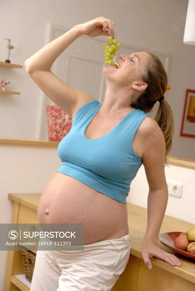 Pregnant woman eating bunch of grapes