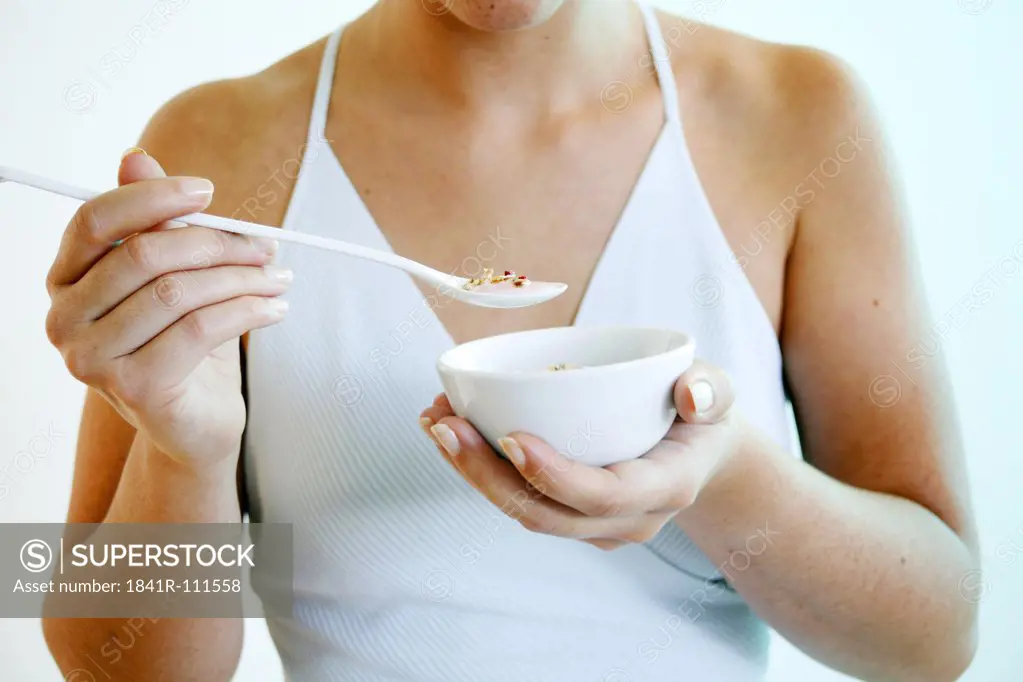 Young woman holds a bowl of cereals.
