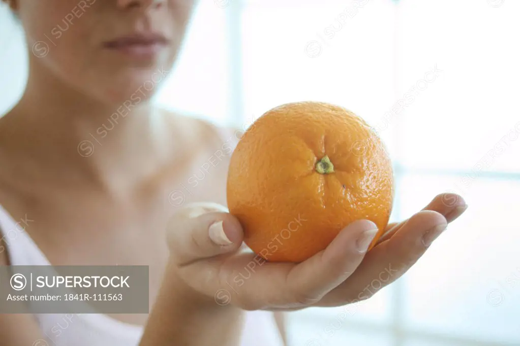 Female hand holding an orange.
