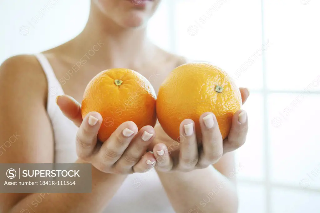 Female hands holding two oranges.