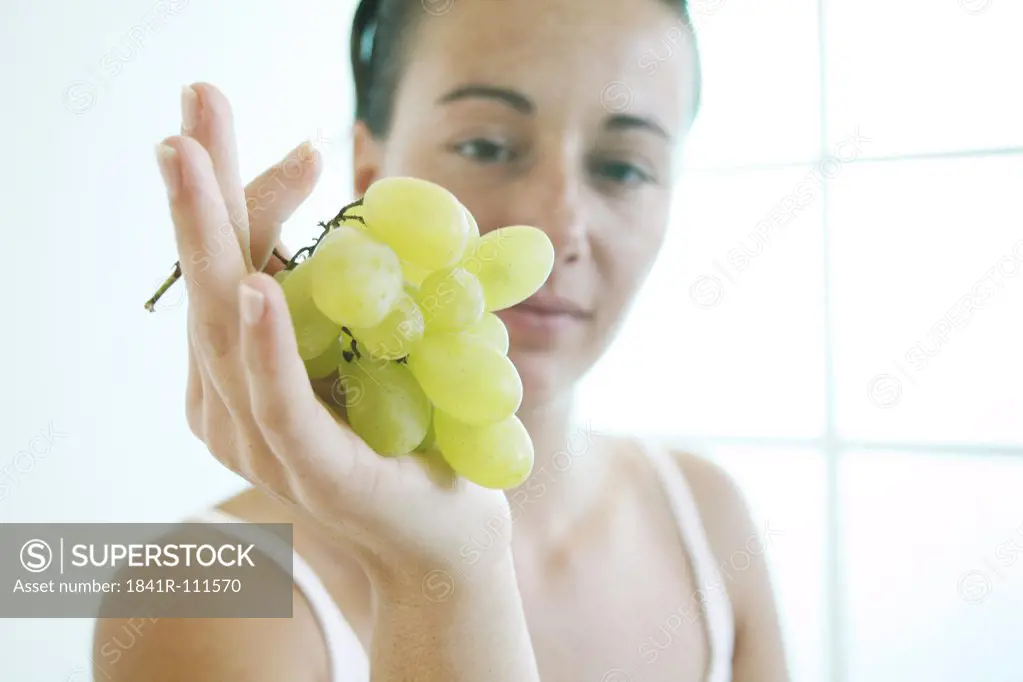 Young woman holds a bunch of grapes..