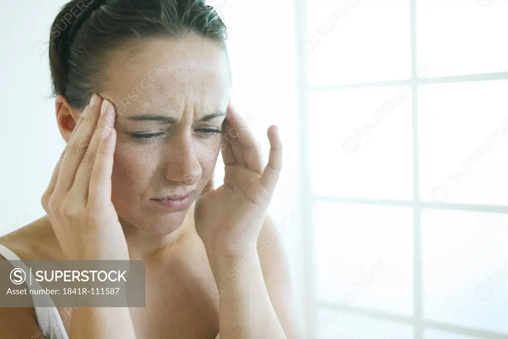 Young woman touches her temples with both hands