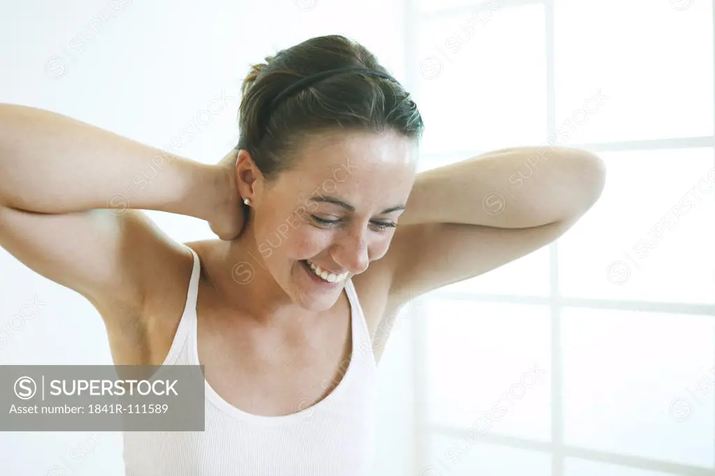 Young woman crosses her hands behind head, laughing