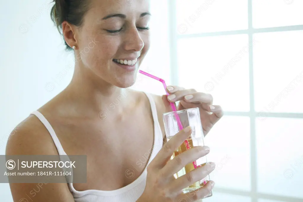 Young woman is drinking juice with a straw.