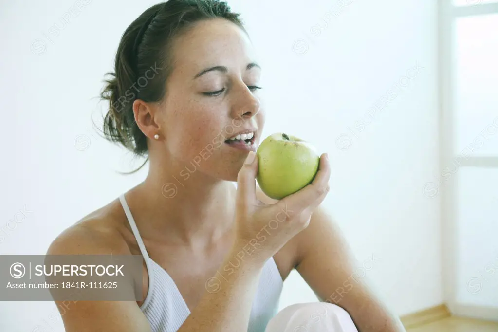 Young woman eating an apple.