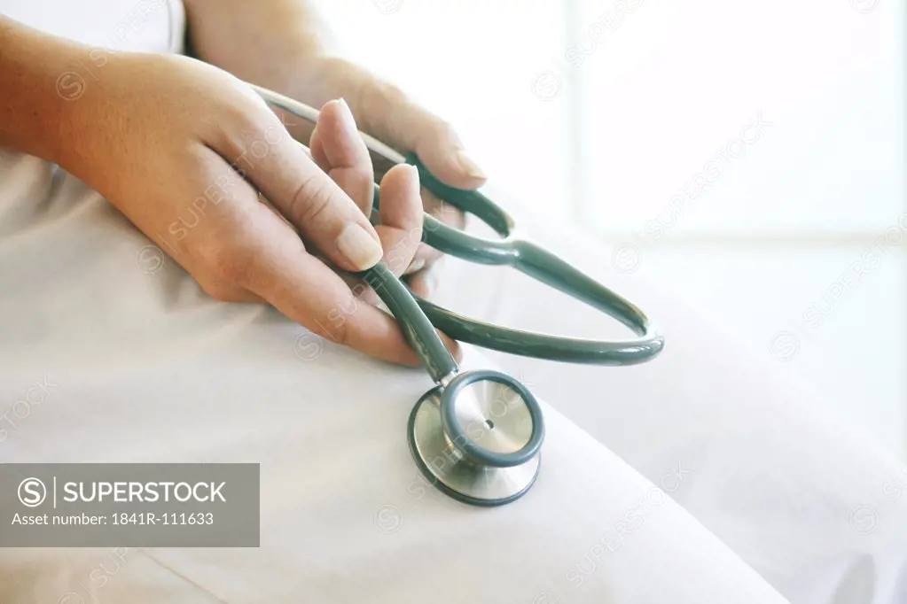 Female hands holding a stethoscope.