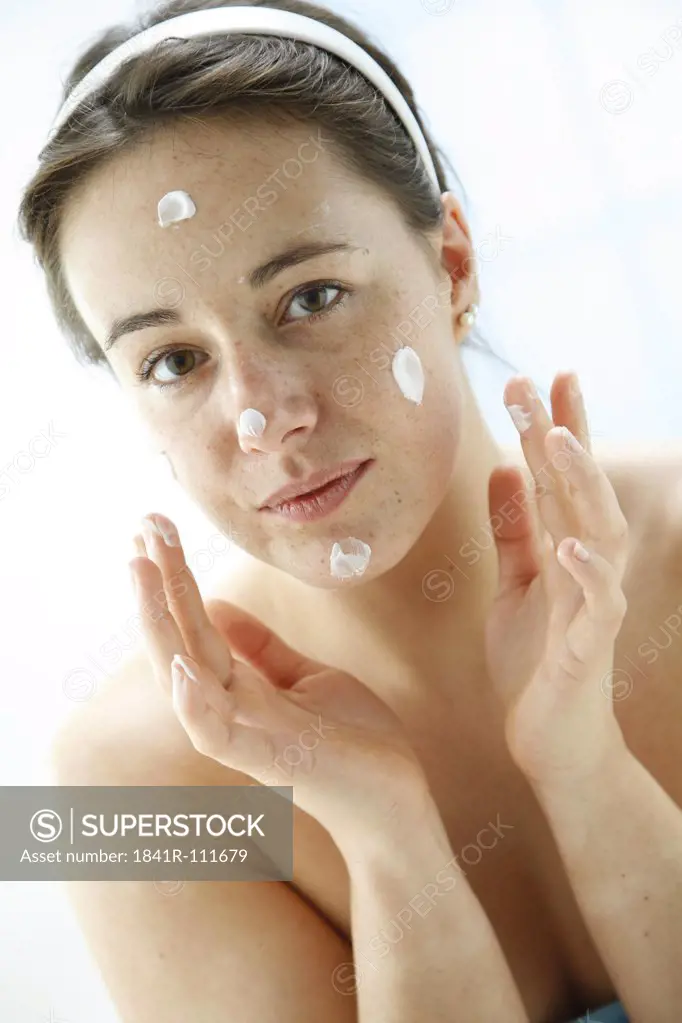 portrait of a young woman using face cream - facial care product