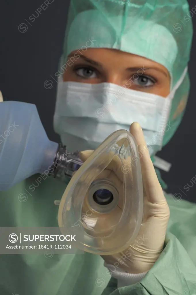 young woman with respiratory mask and ambu bag in an operation room. She is wearing a mouth mask and a bonnet