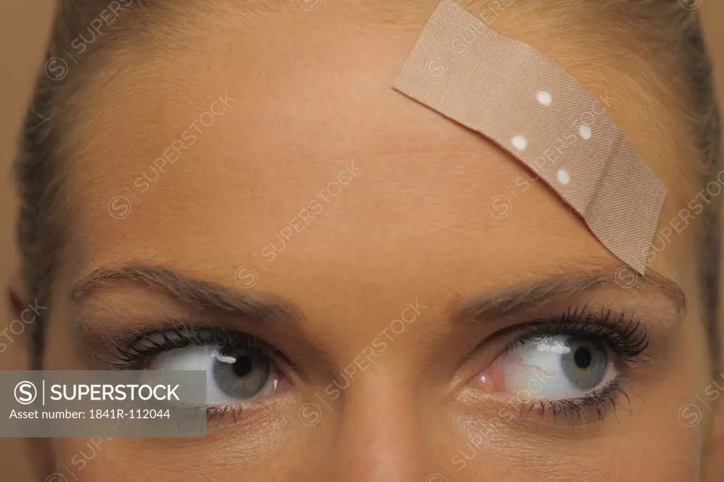 Young woman with a plaster on her forehead