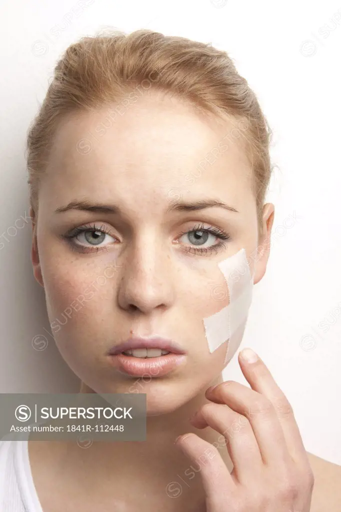 Young woman with plaster in her face