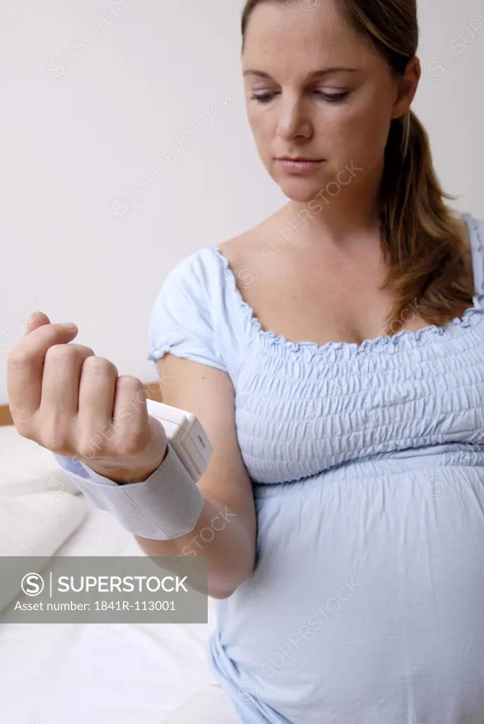 pregnant woman meassuring her arterial blood pressure