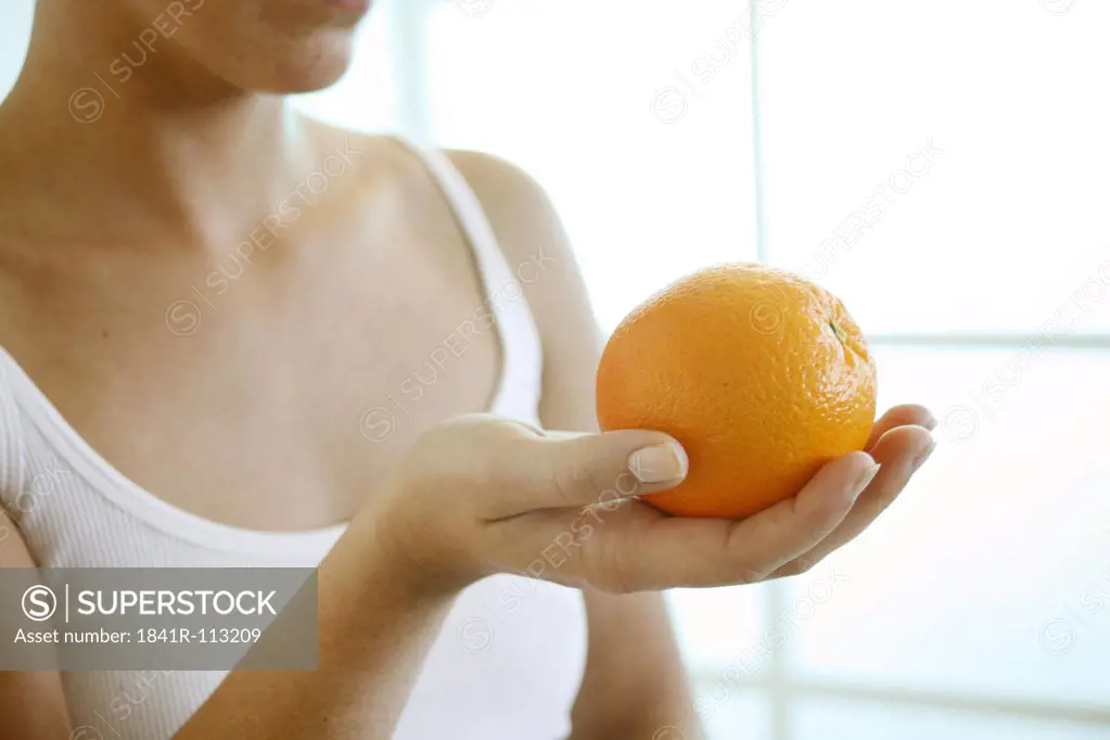 Female hand holding an orange.