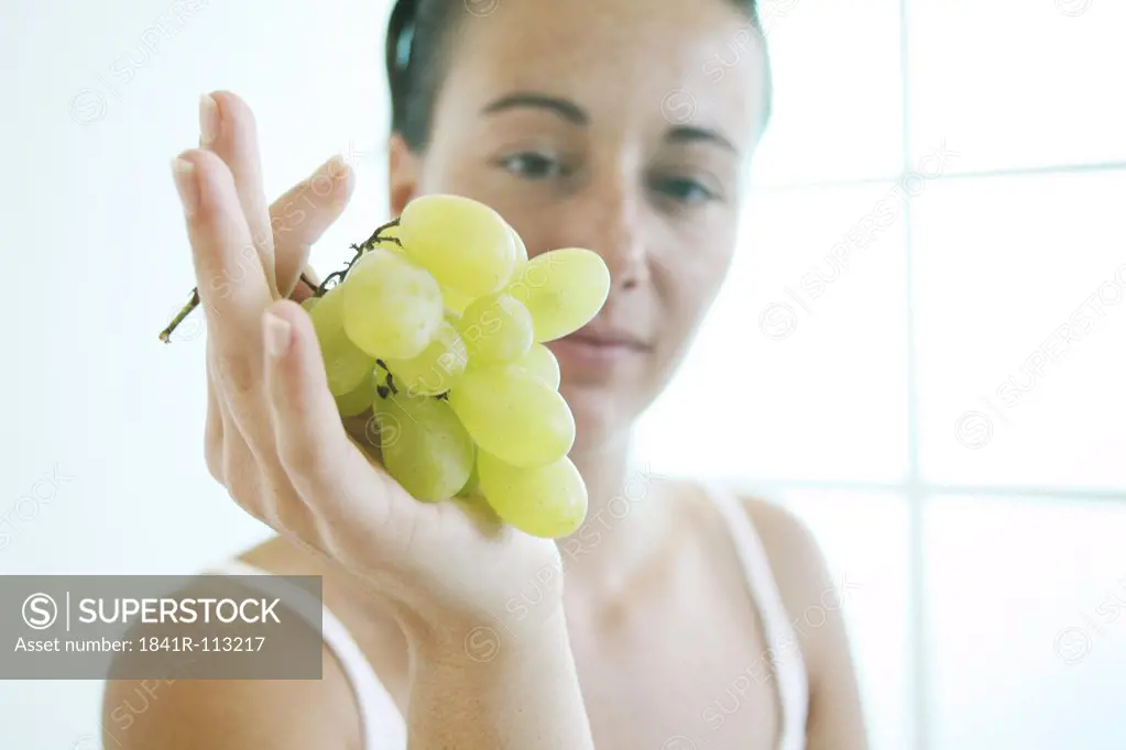 Young woman holds a bunch of grapes..