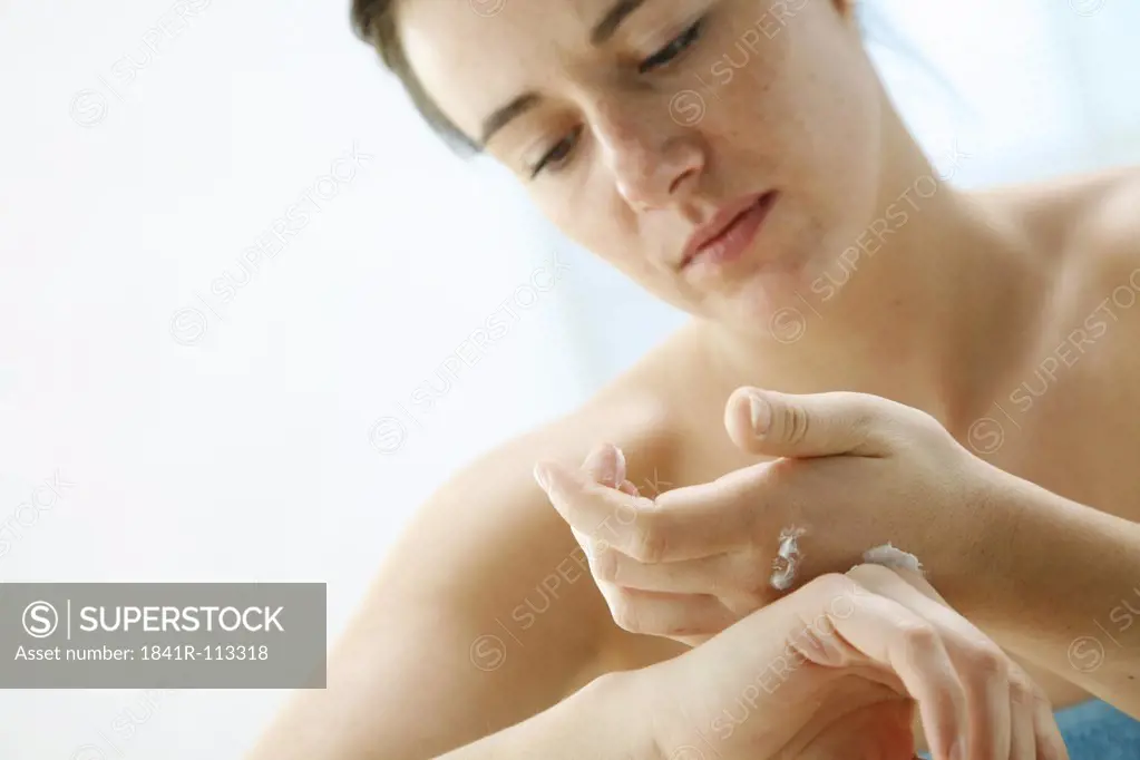 young woman using hand lotion