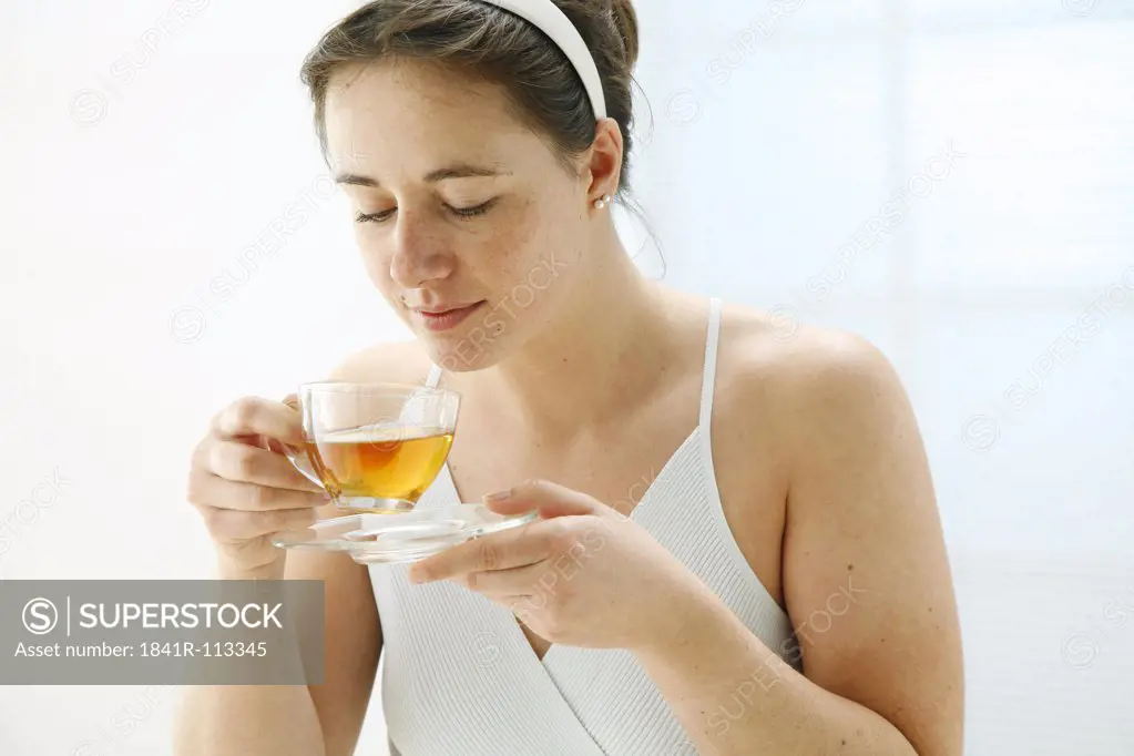 young woman holding a cup of tea in her hands and is taking a smell on it