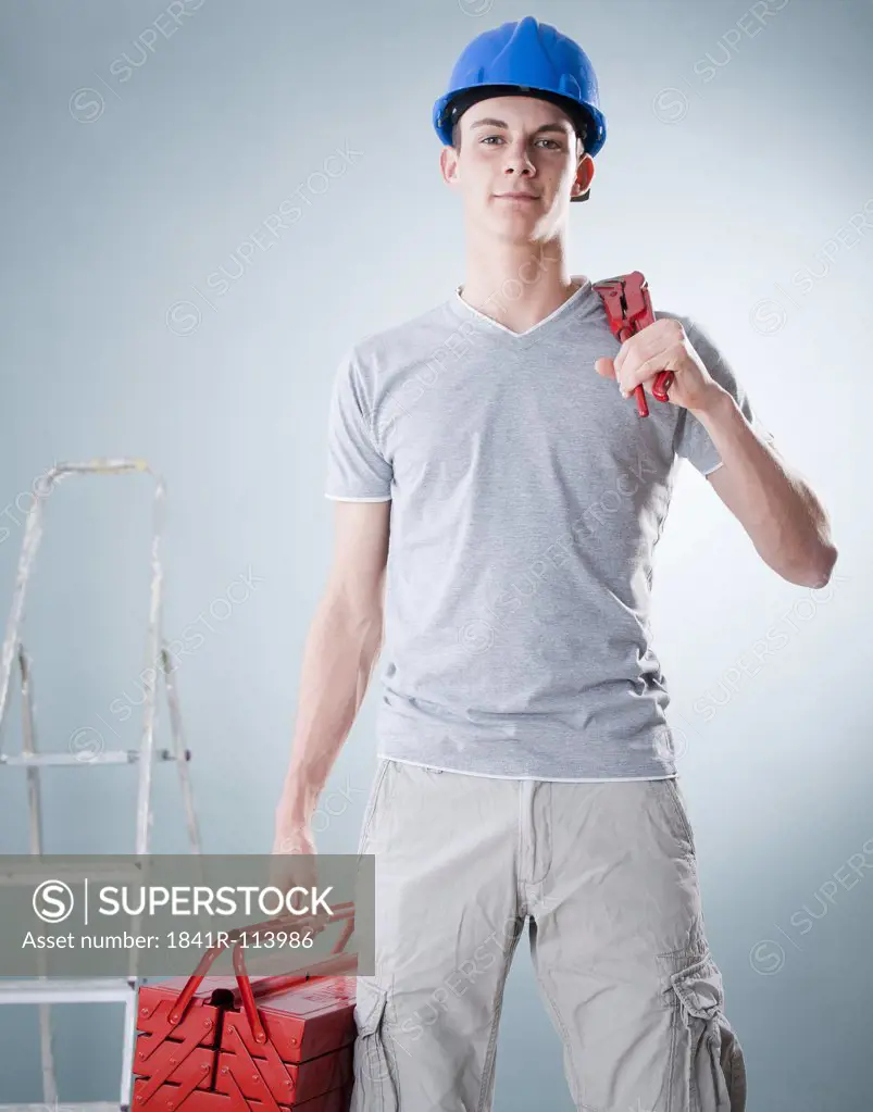 Young man wearing hard hat holding tools