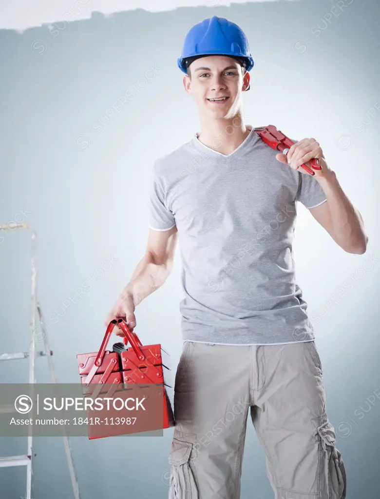 Young man wearing hard hat holding tools