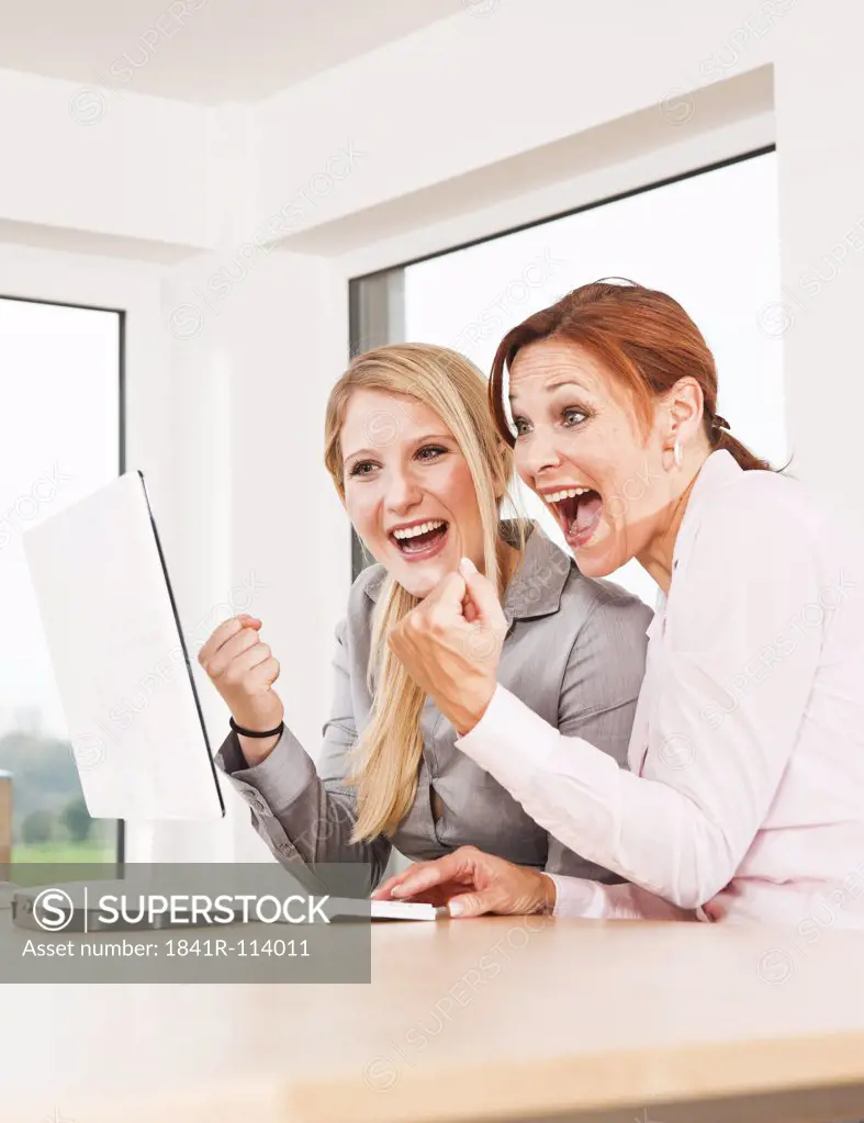 Two businesswomen at desk cheering