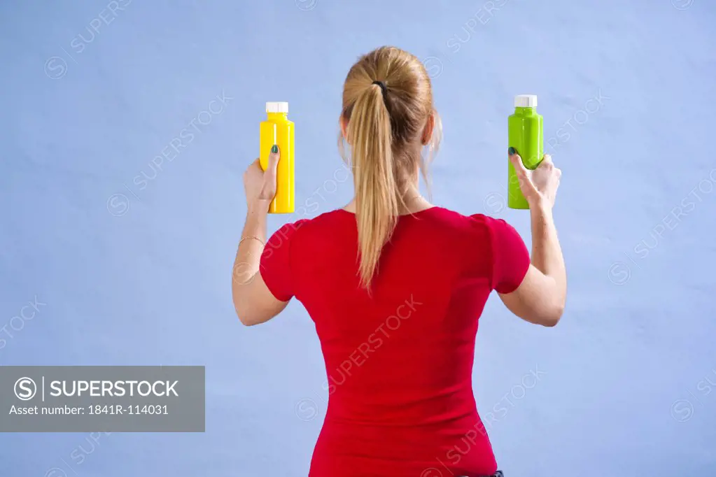 Young woman standing with paint tins at a wall