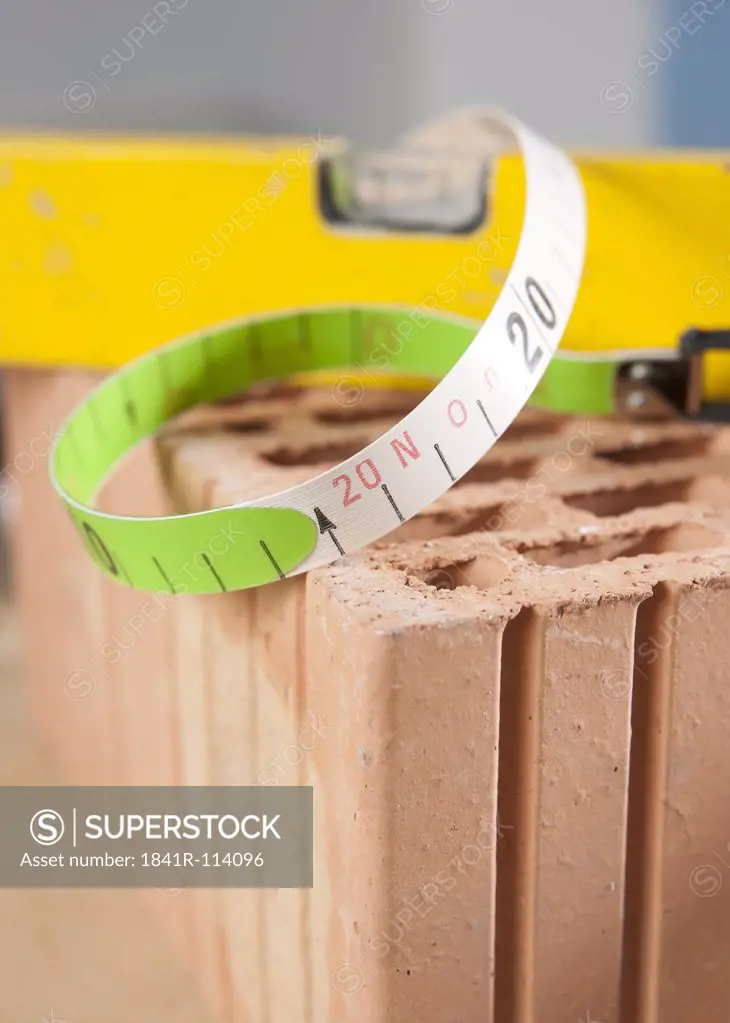 Measuring tape, mechanic's level and claybrick