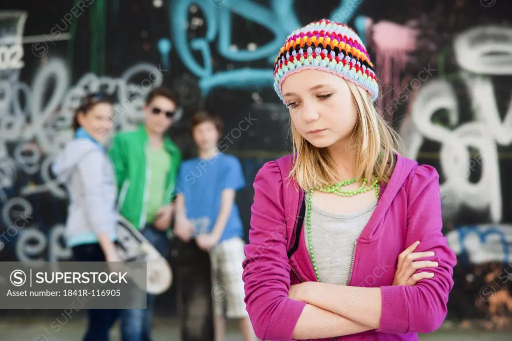 Sad teenage girl with three teenagers in background