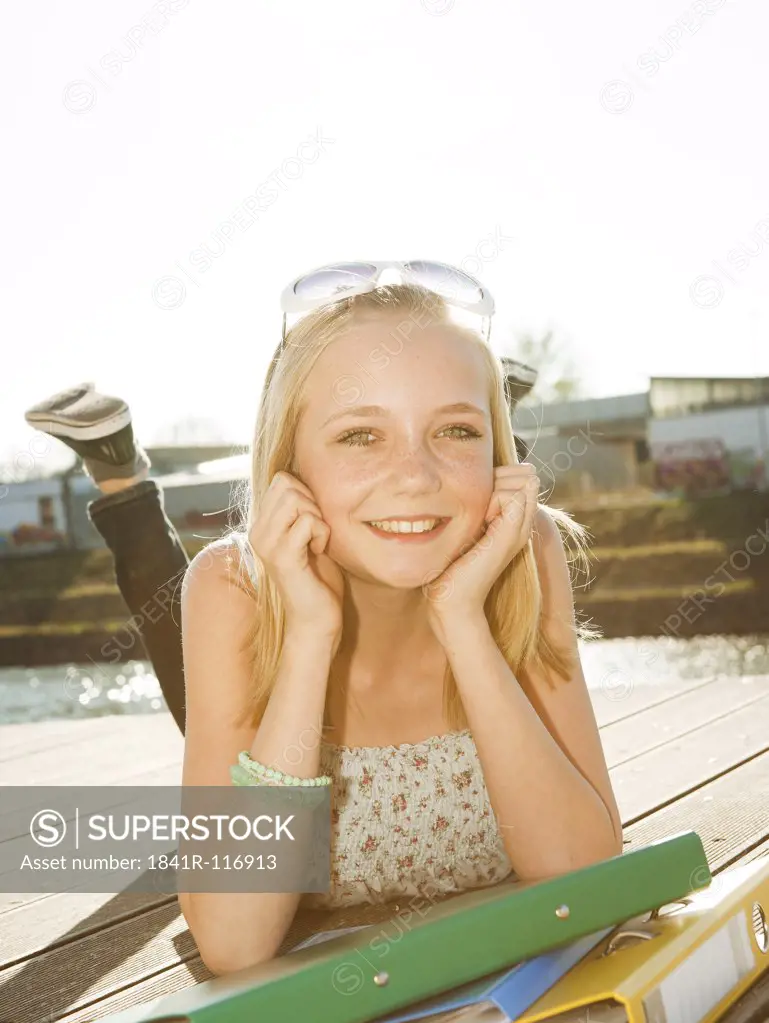 Smiling teenage girl lying on jetty