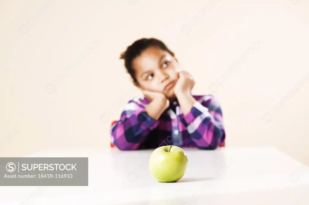 Girl sitting at table with an apple