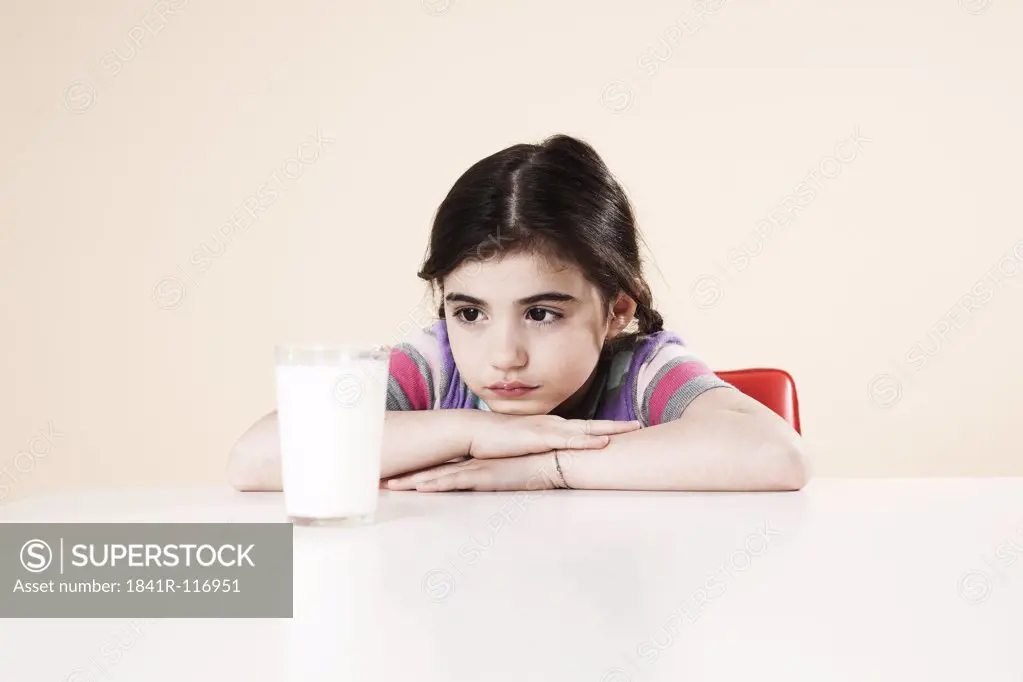 Girl sitting at table with a glass of milk