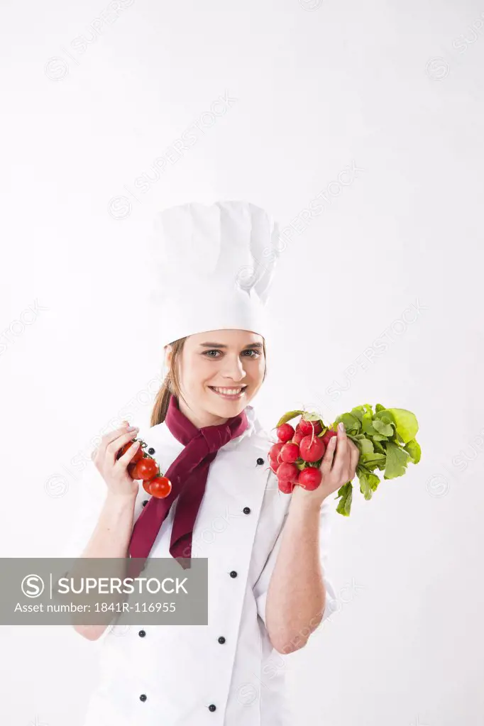 Smilig chef holding radish and tomatoes