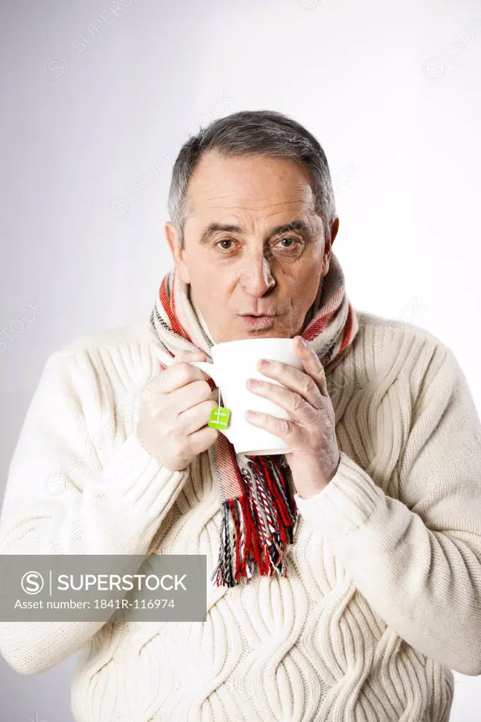 Senior man in winter clothes drinking cup of tea