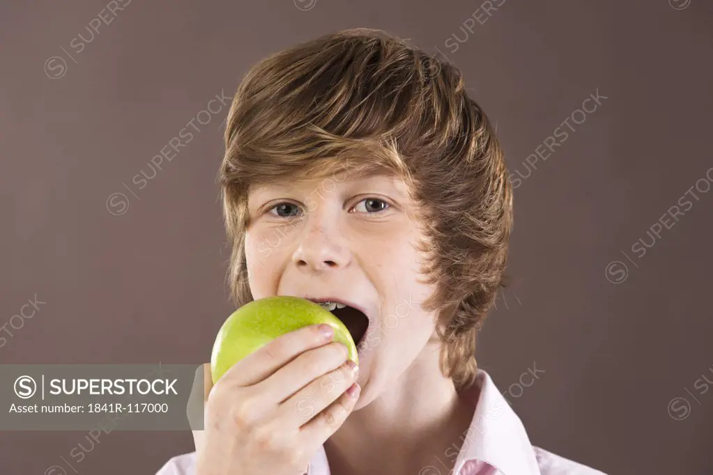 Teenage boy eating an apple, portrait