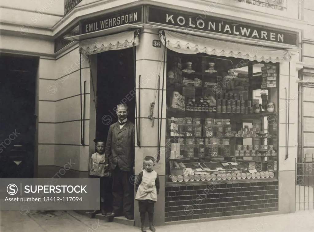Historical picture of a storekeeper in front of his grocery