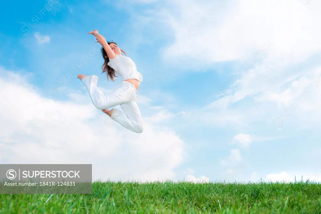 Young woman jumping on meadow