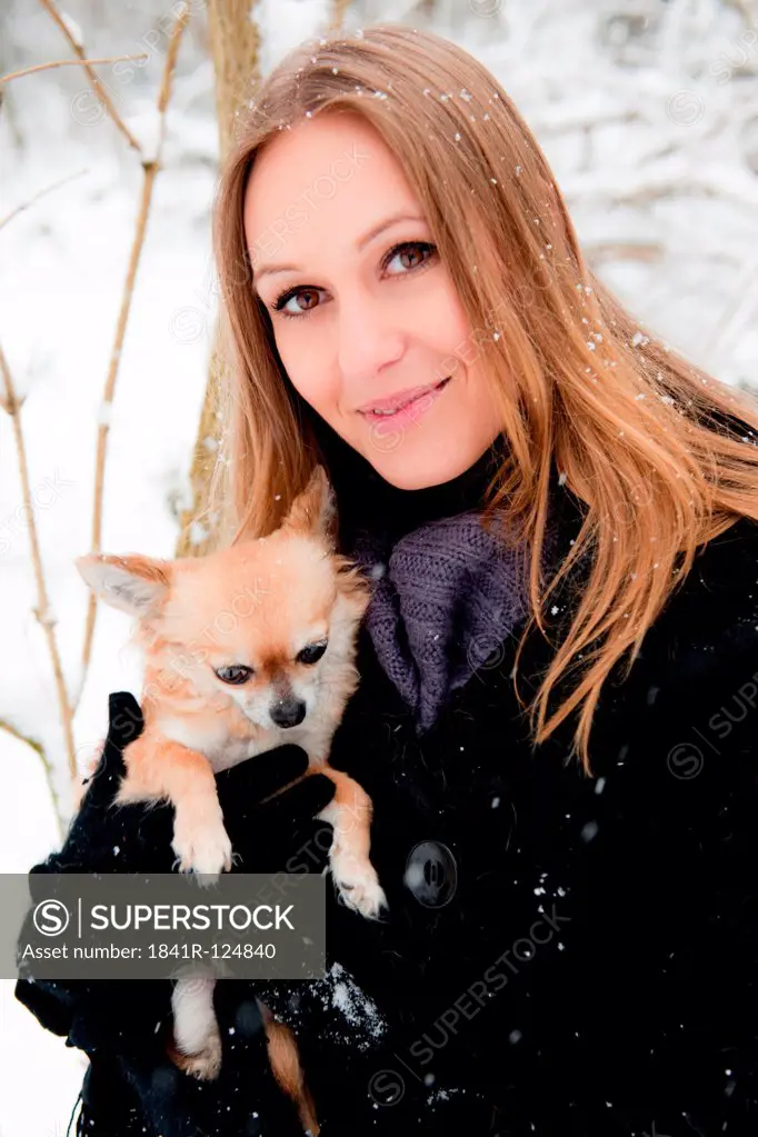 Young woman with dog in snow, portrait