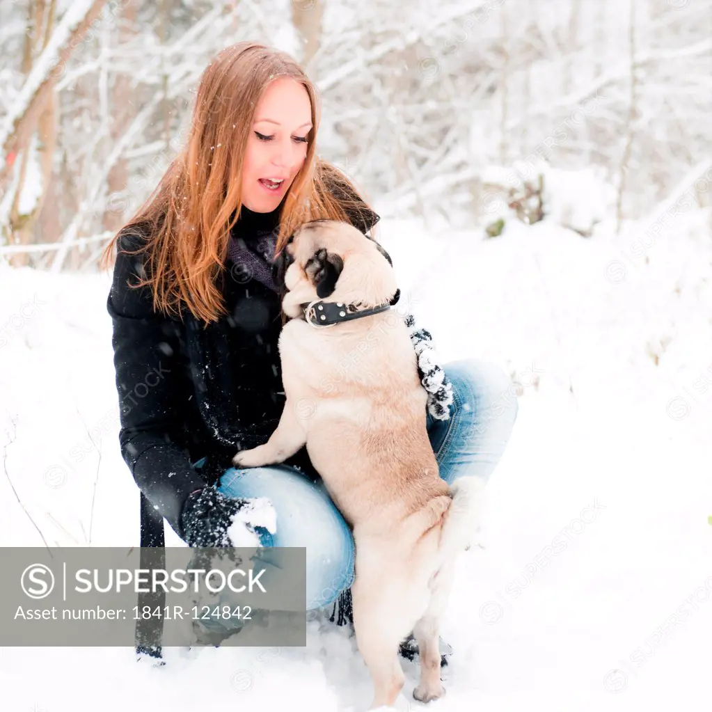 Young woman with pug dog in snow