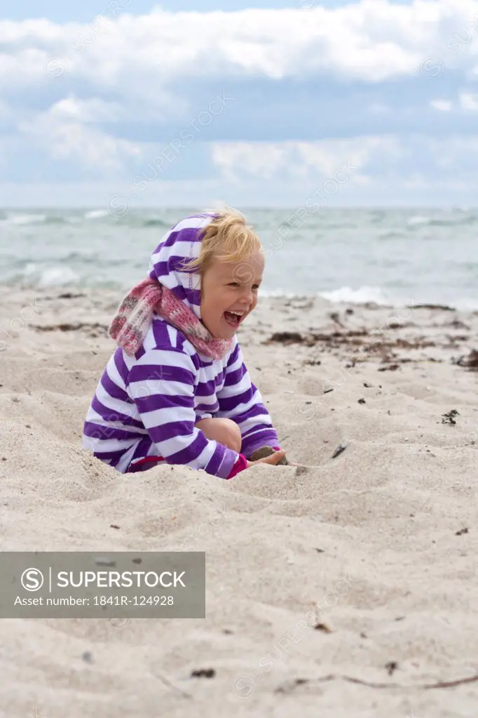 Happy girl playing in sand on the beach