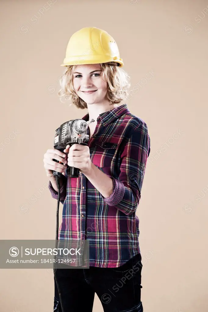 Teenage girl with hard helm and drill machine