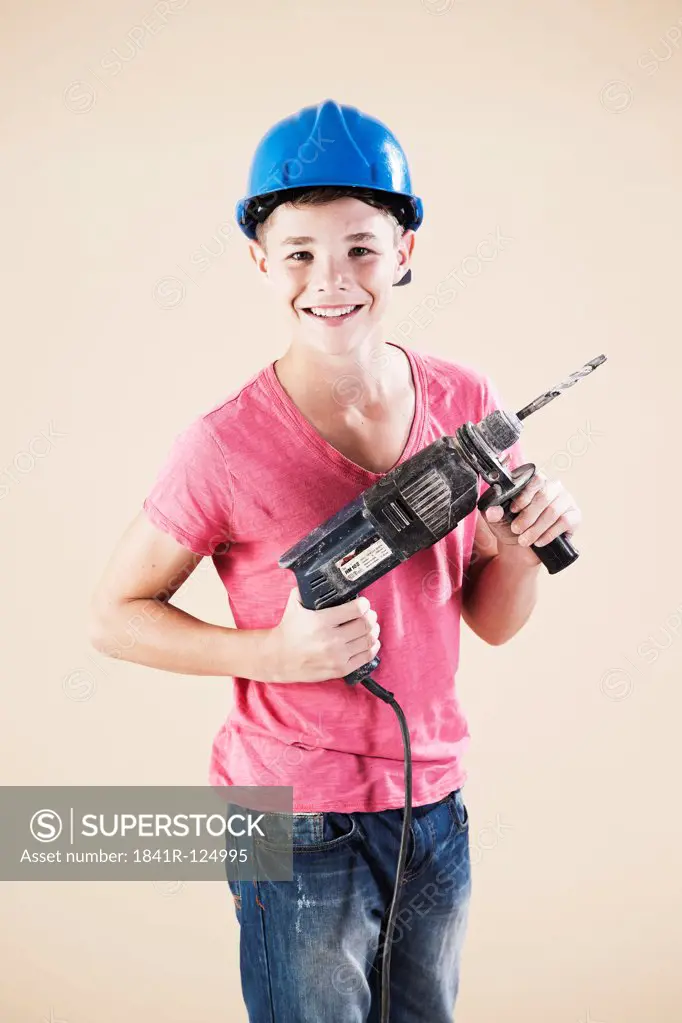 Teenage boy with hard helm and drill machine