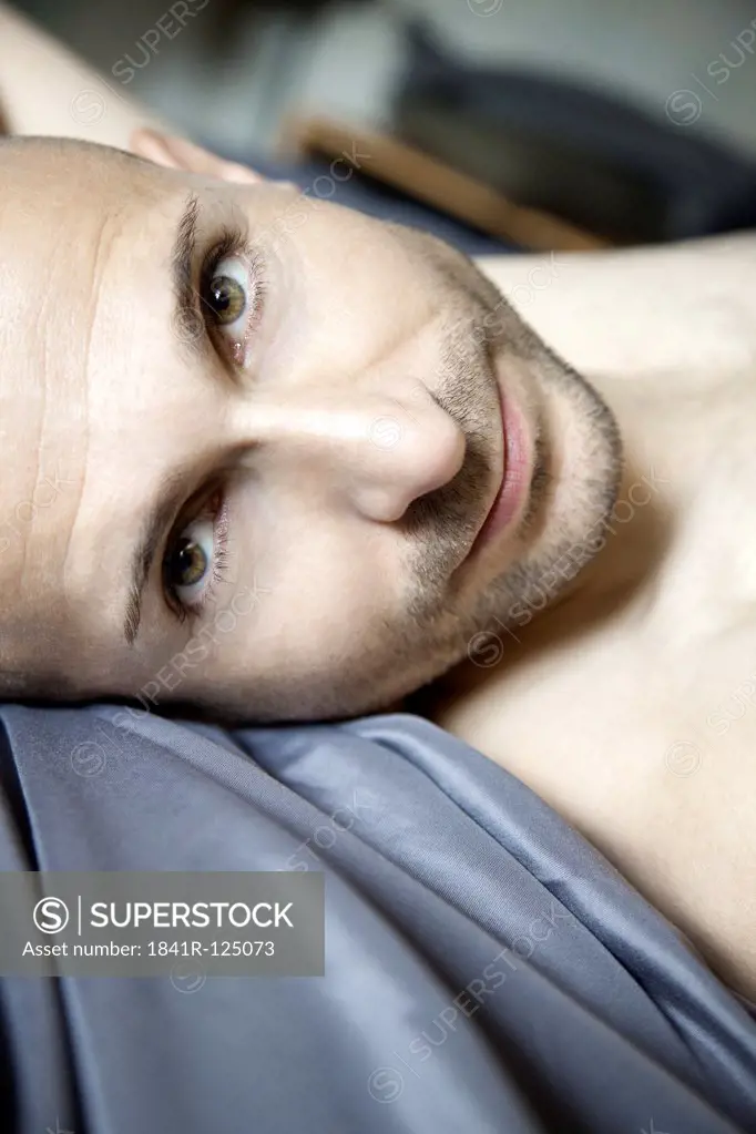 Man with designer stubbles lying in bed, portrait