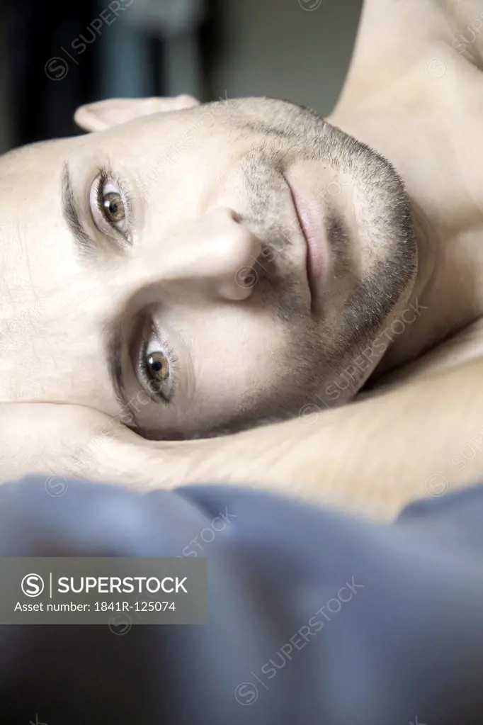 Man with designer stubbles lying in bed, portrait