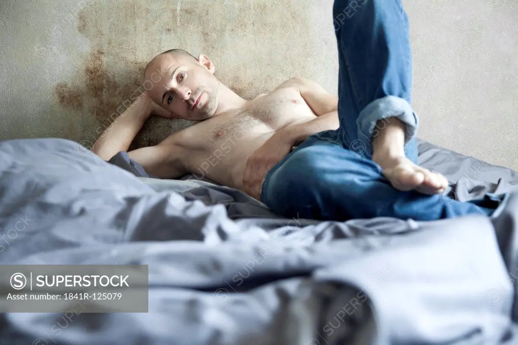 Barechested man with designer stubbles on bed