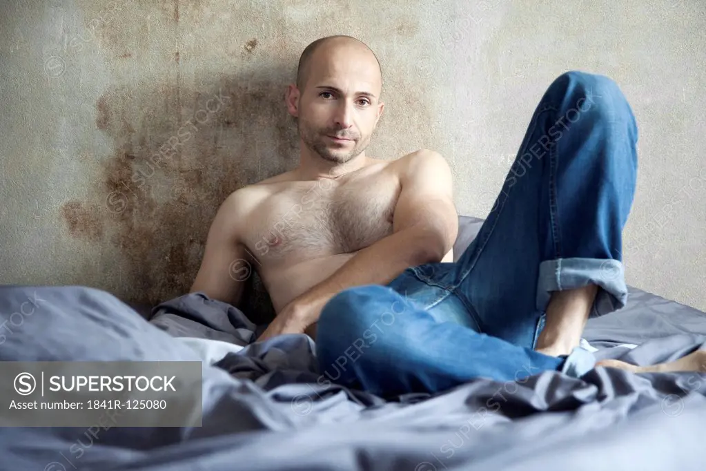 Barechested man with designer stubbles on bed