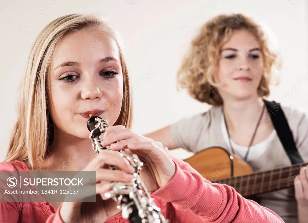 Two teenage girls playing guitar and oboe